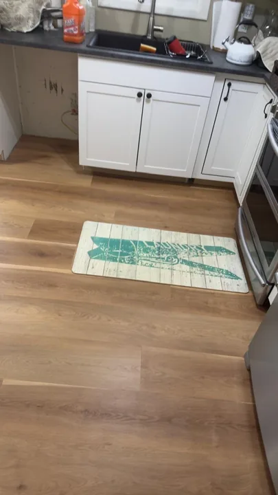 Warm wide-plank flooring beside white kitchen cabinets